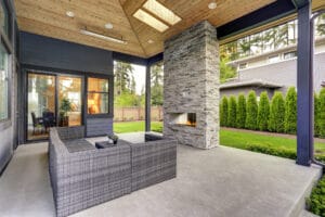 Concrete Patio Sealer, A modern outdoor living area with a fireplace, enhanced by commercial cleaning services for the roof and exterior.
