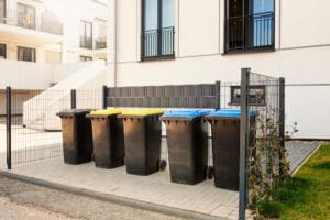 Outdoor Wheelie Bins, Maggots, A group of trash cans in front of a building undergoing Exterior Cleaning.