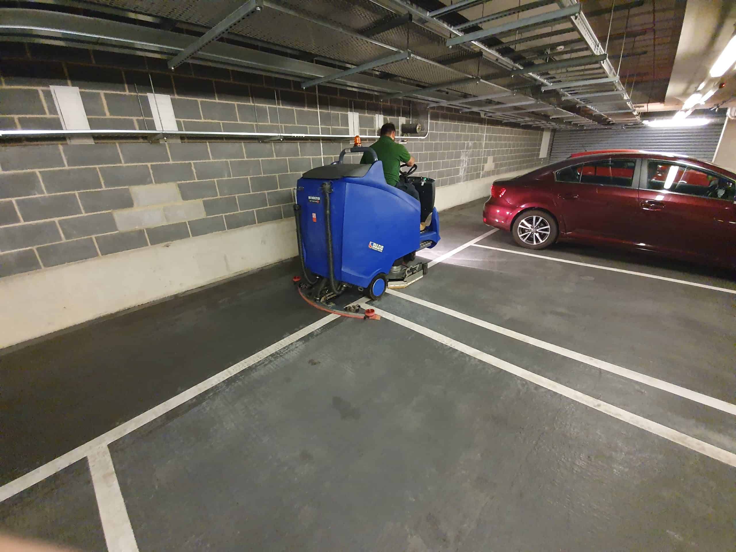 Multi Level Car Park, A man performing commercial cleaning in a parking garage with a blue machine.