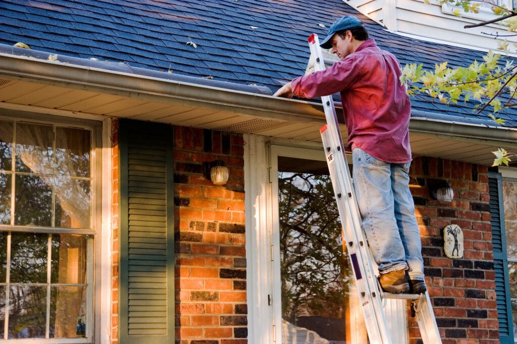 5 Benefits of Hiring a Roof Cleaning Company in London, Man Cleaning Gutters