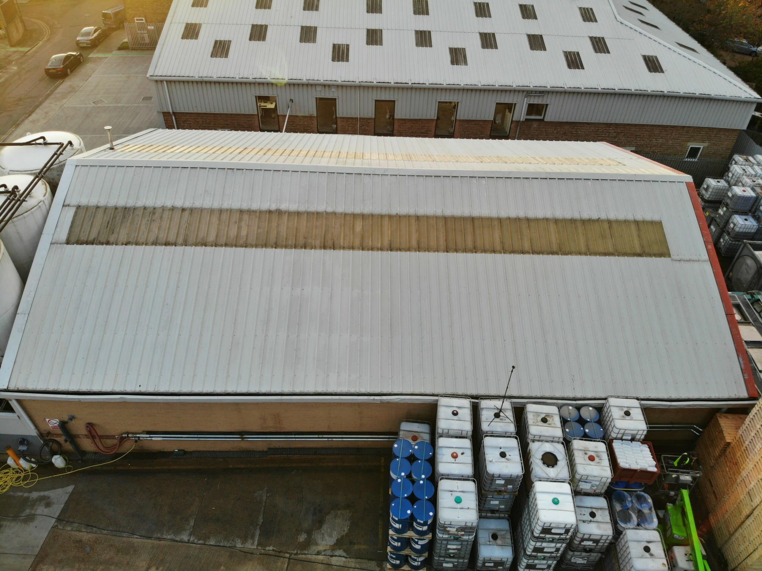 After: An aerial view of a large warehouse undergoing roof cleaning.