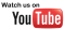 The image features the text "Watch us on" in black, followed by the YouTube logo. The logo consists of the word "YouTube," with "You" in black and "Tube" in white inside a red play button icon. The background of the image is transparent.
